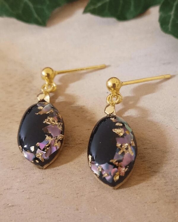 Boucles d'oreilles féminines en nacre rose et feuilles d'or sur fond noir. Style raffiné et élégant