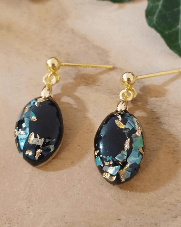Boucles d'oreilles pendantes en nacre verte et feuilles d'or sur fond noir