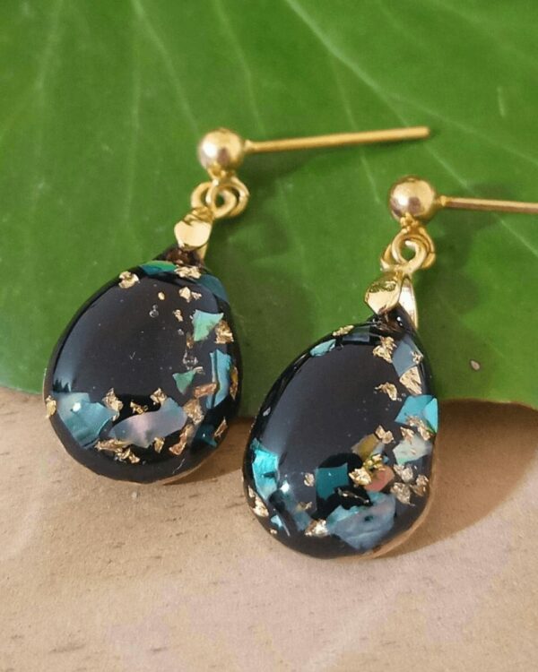 Boucles d'oreilles en nacre et feuilles d'or sur fond noir. Le tout en argent Sterling 925 plaqué or. Bijoux pour femmes.