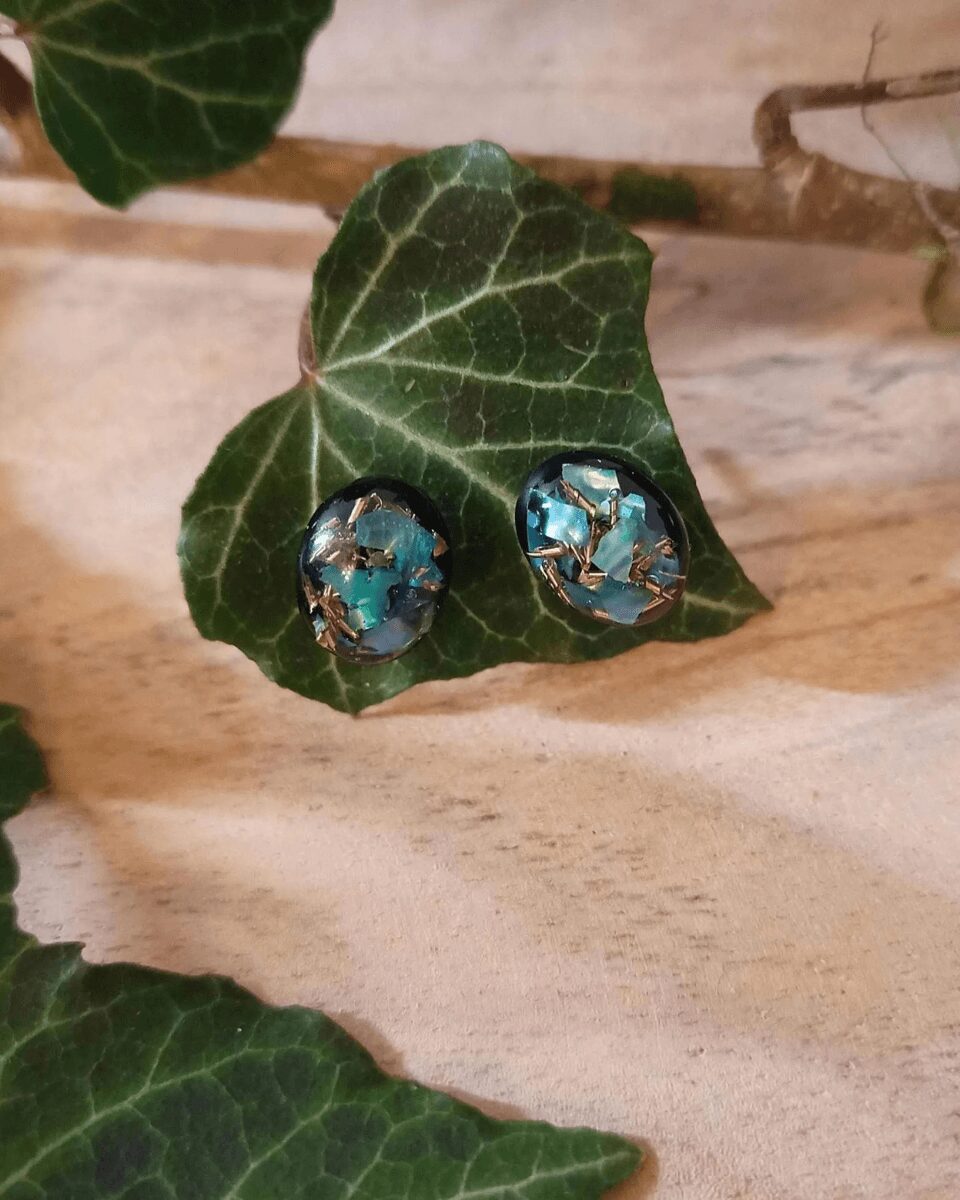 Clous d'oreilles en nacre verte et éclat de laiton sur fond noir. Style mystérieux s'inspirant de la magie des aurores boréales.