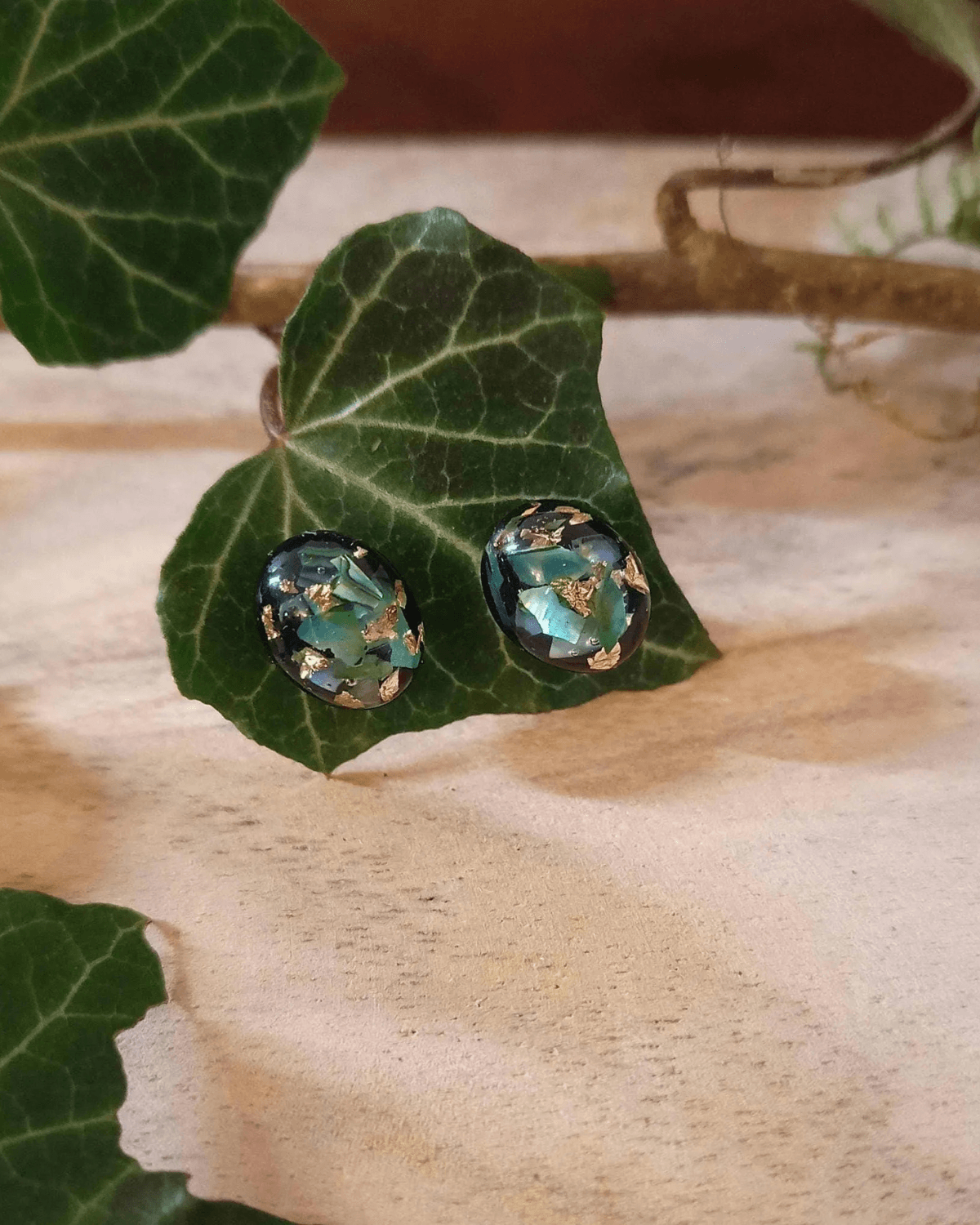 Cabochons d'oreilles en nacre verte et feuilles d'or sur fond noir